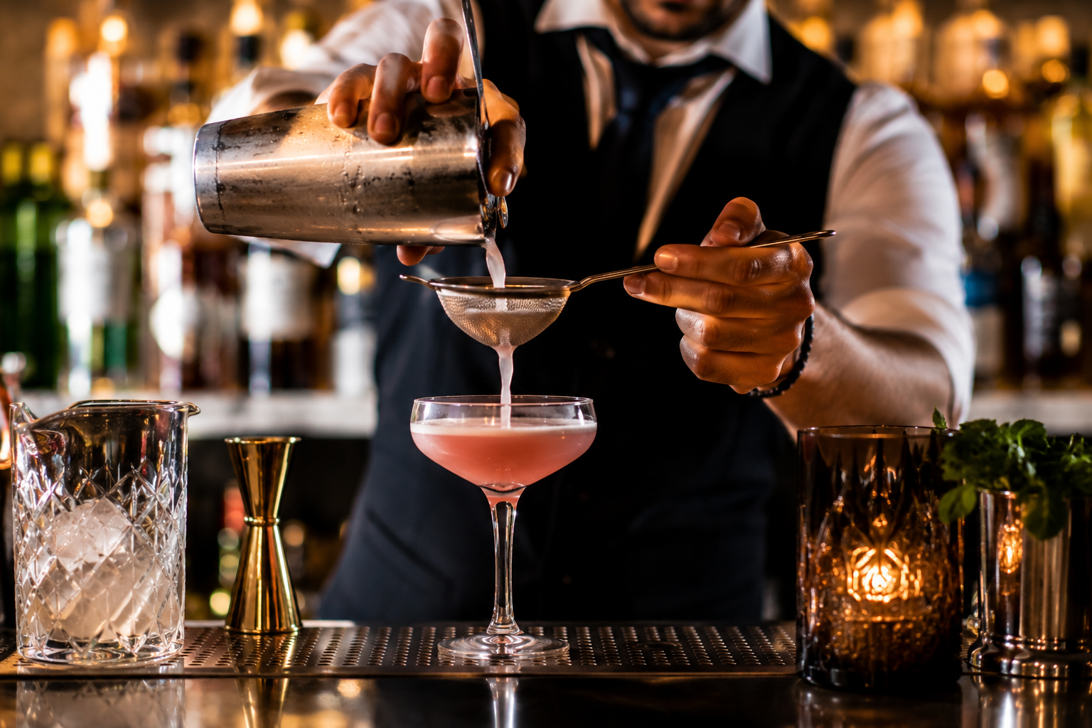 Bartender pouring a craft cocktail through a strainer